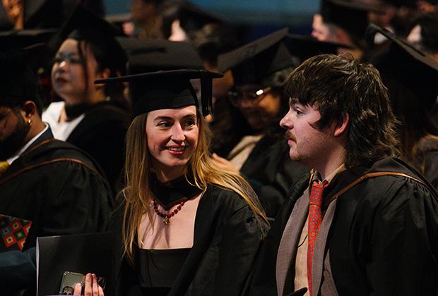 Two graduates in the hall sitting waiting