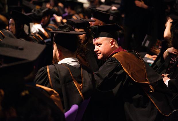 Two graduates sitting waiting taken from behind 