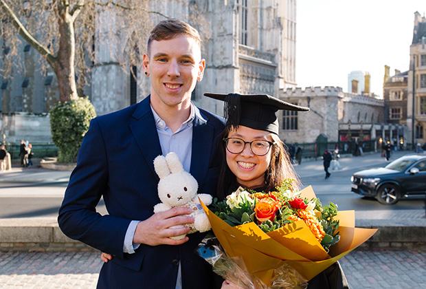 Graduate and their guest holding a little toy rabbit