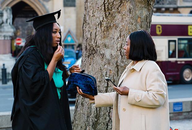 A graduate checks her lipstick outside