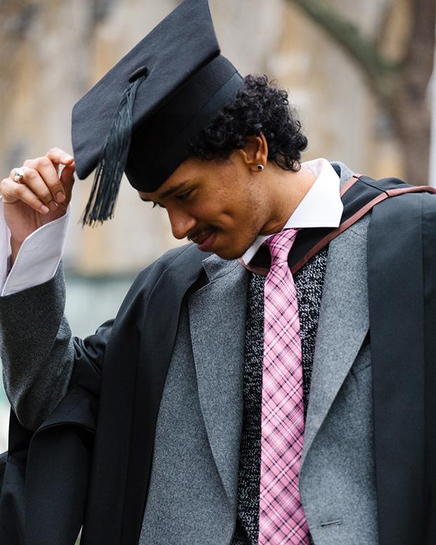 Graduate in a pink tie tipping his mortar board hat