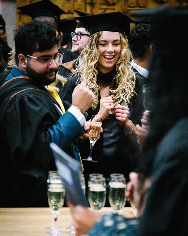 Two graduates excited to get their glasses of fizz
