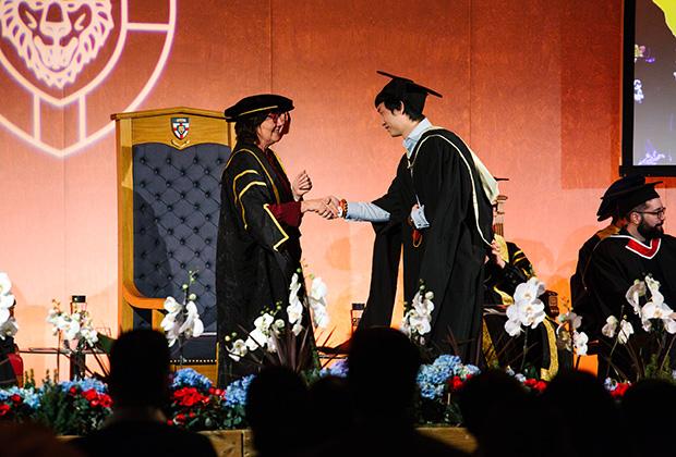 Graduate shakes hands with the master of the ceremony