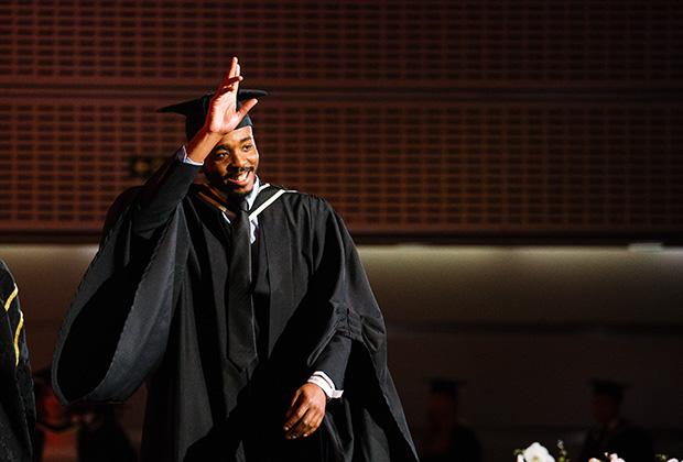 Graduate crossing the stage waves to the audience