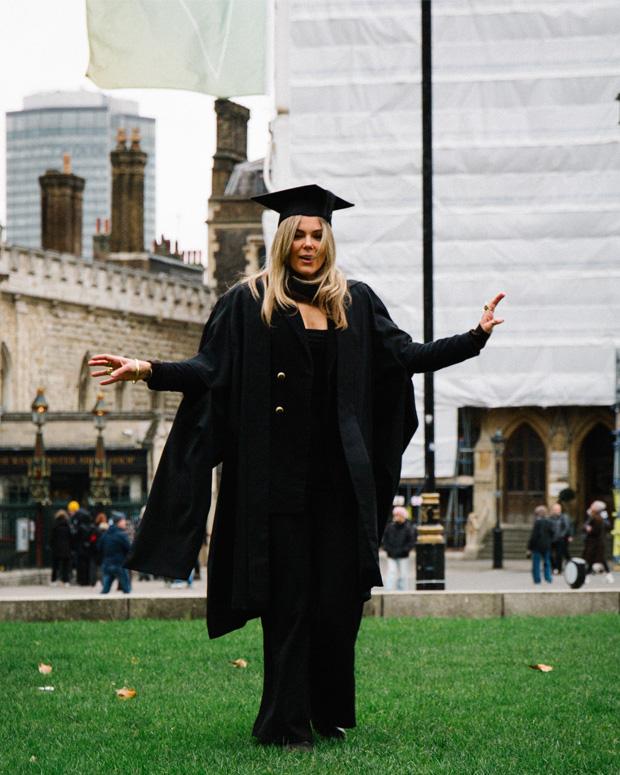 A woman poses in a graduation robe 