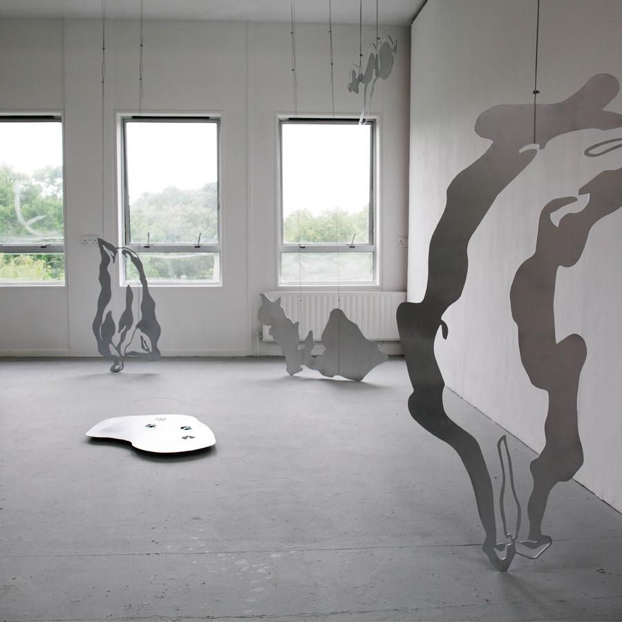 Metal shapes cast shadows on a white exhibition space.