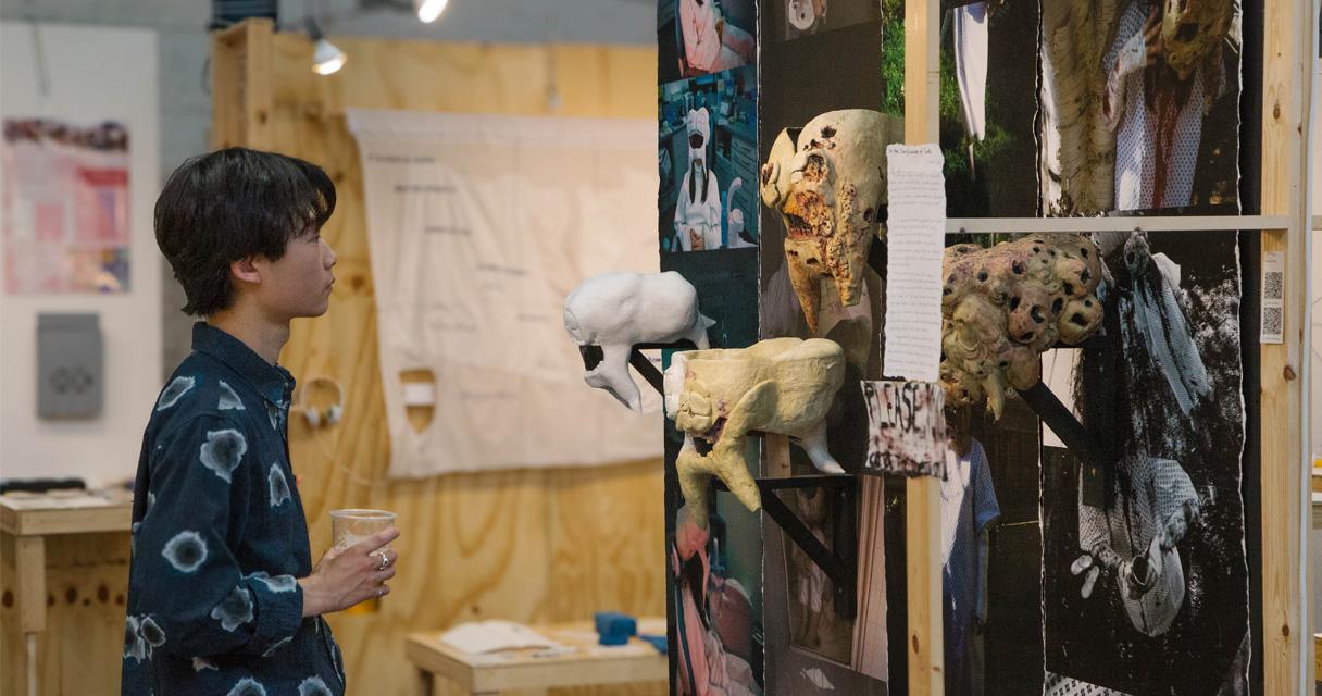 A man stands infront of a display of cast masks and teeth. 