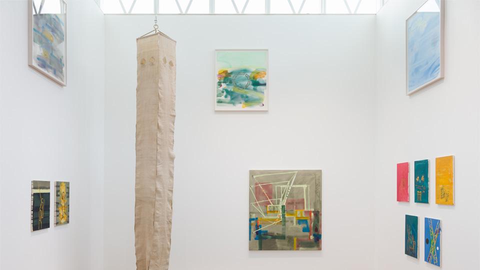 A light-filled exhibition space with brightly coloured paintings, installations.