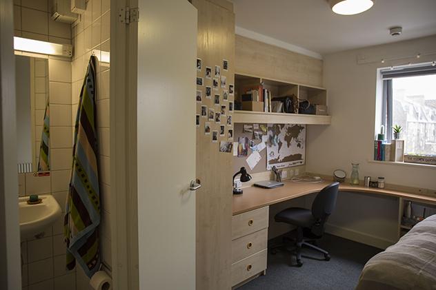 Inside a room in halls where you can see inside a small en suite bathroom as well as built-in storage in the bedroom
