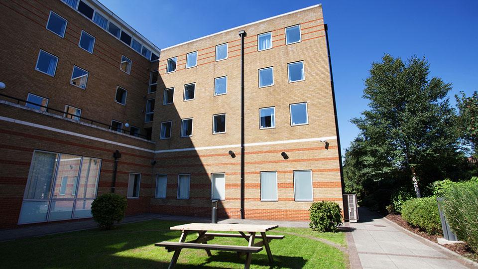 Outside Ewen Henderson Court halls a modern brick building with a grass courtyard and picnic benches
