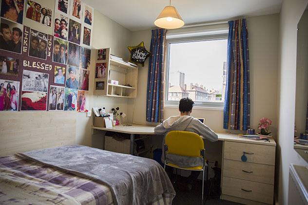 A male student sitting in his room in halls