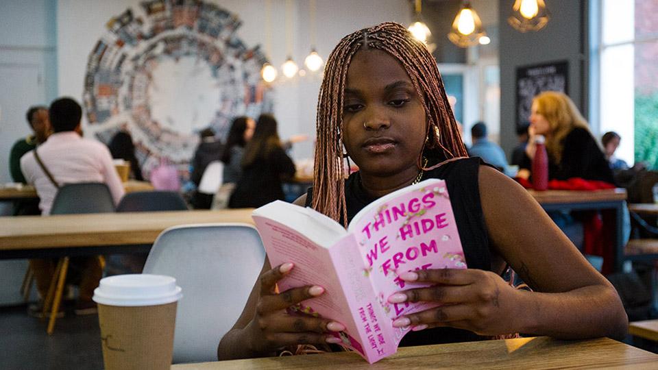 A student reading, with a cup of coffee sitting in front of them