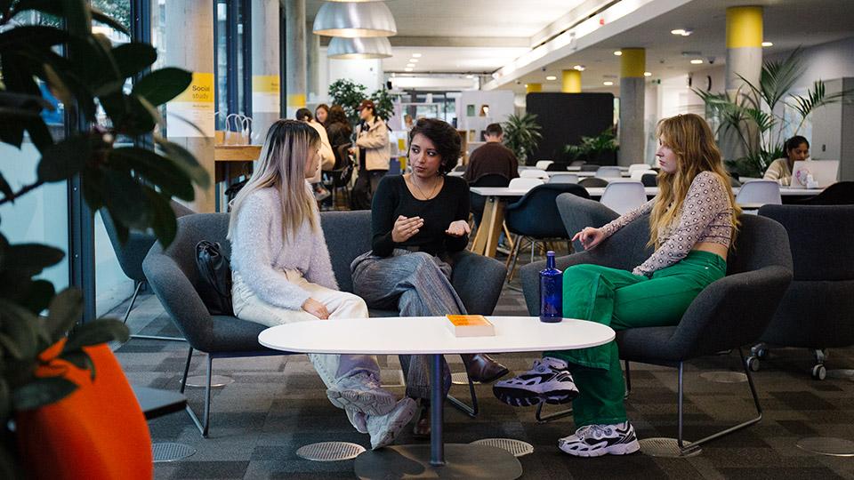Three students chatting on a sofa in the Library