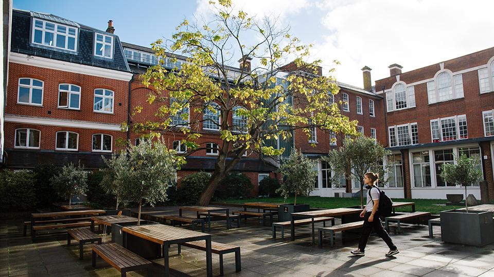 Student walking through the Quad surrounded by tables and benches