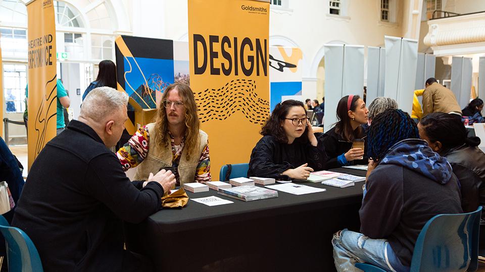 Prospective students speaking to academics at an open day desk