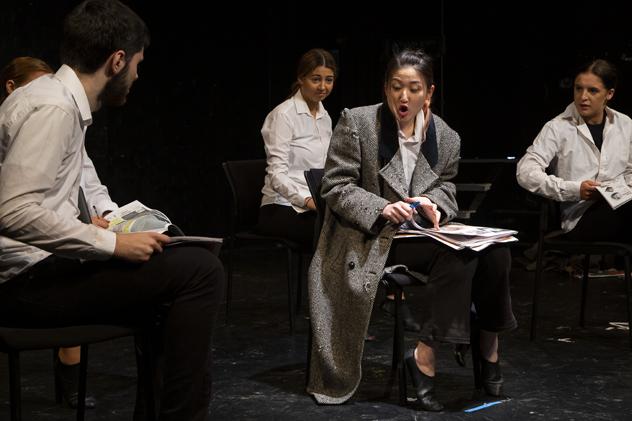 A musical theatre production, featuring four students sitting on chairs while wearing formal clothing