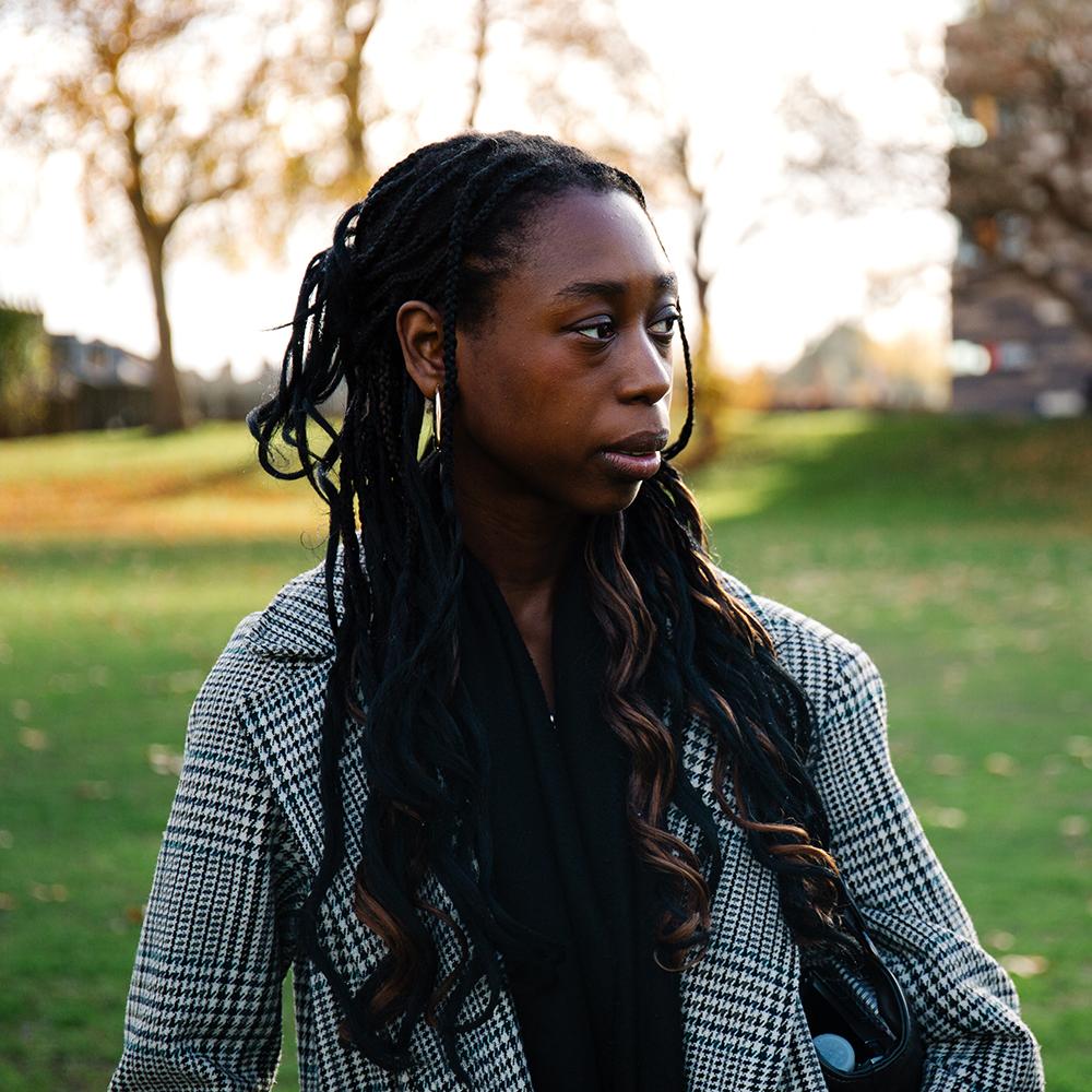 A girl thoughtfully looking to the side, with green grass and clear skies in the background