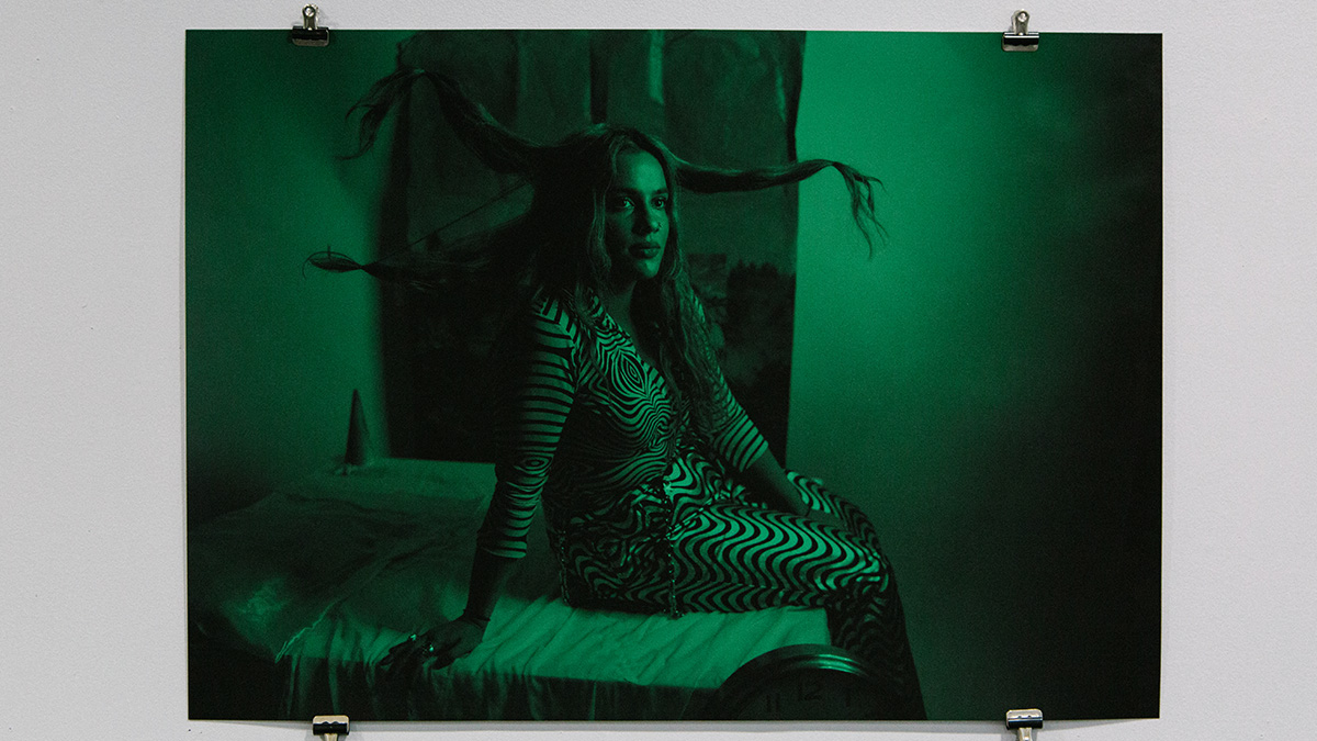 A photograph lit in a green hue shows a woman sitting down. Her hair is floating in different directions.